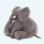 Peluche d'un éléphant gris assis. Il a de grandes oreilles et des défenses. La peluche en coton est moelleuse.