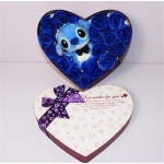 La peluche bleue de Stich est dans une boite en forme de coeur. Il y a des roses bleues tout autour de lui. Sur le couvercle de la boîte, il y a un ruban violet des inscriptions et des motifs coeurs. Stich porte un noeud papillon noir.