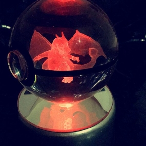 Boule lumineuse à l'apparence d'une pokéball. Il y a un Pokémon à l'intérieur. La boule en verre tourne sur elle même grâce à son socle en plastique.