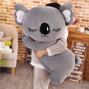 Peluche koala grise oreiller, bonne qualité et confortable, porté par une petite fille dans une maison.
