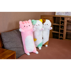 Sur un canapé gris dans un petit salon au sol marron, 3 peluches oreillers à l'effigie de grand chat debout, se tiennent appuyées sur le canapé , l'un est rose, le 2ème est vert et le 3ème est marron