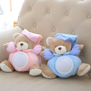 Peluche musical ours bruit blanc dont l'un est habillé en bleu et l'autre en rose assis sur un canapé de couleur beige