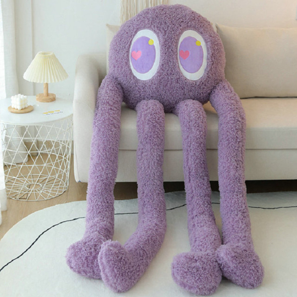 Oreiller en peluche en forme de pieuvre géante violette avec de grands yeux, elle est installée sur un canapé près d'une petite table avec une lampe