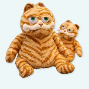 Deux peluches du même modèle d'un chat tigré roux assis sur un support en bois, le premier grand et celui en arrière-plan de petite taille
