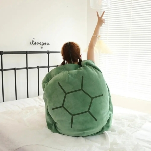 Femme assise sur un lit dans une chambre, un bras en l'air et portant un coussin en forme de tortue vert sur le dos