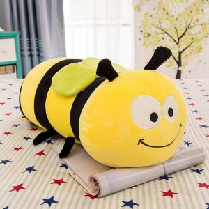 on voit une peluche coussin abeille souriante jaune et noire sur une table qui a une nappe avec des étoiles rouges et bleues dessus