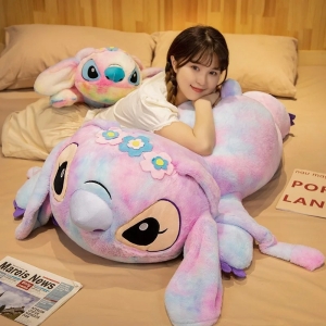 On voit une femme asiatique sur un lit et sur un coussin géant peluche du personnage Angel dans Stitch