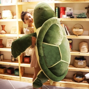 on voit une jeune femme porter une peluche géante de tortue verte dans une chambre