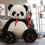 on voit une peluche panda scout géante avec une jeune fille habillée en scout assise par terre