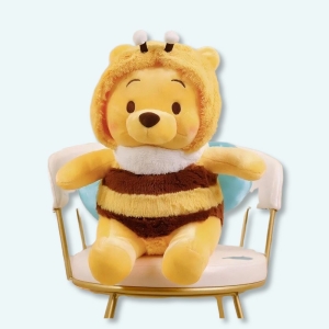on voit une peluche winnie l'ourson déguisé en abeille sur une chaise
